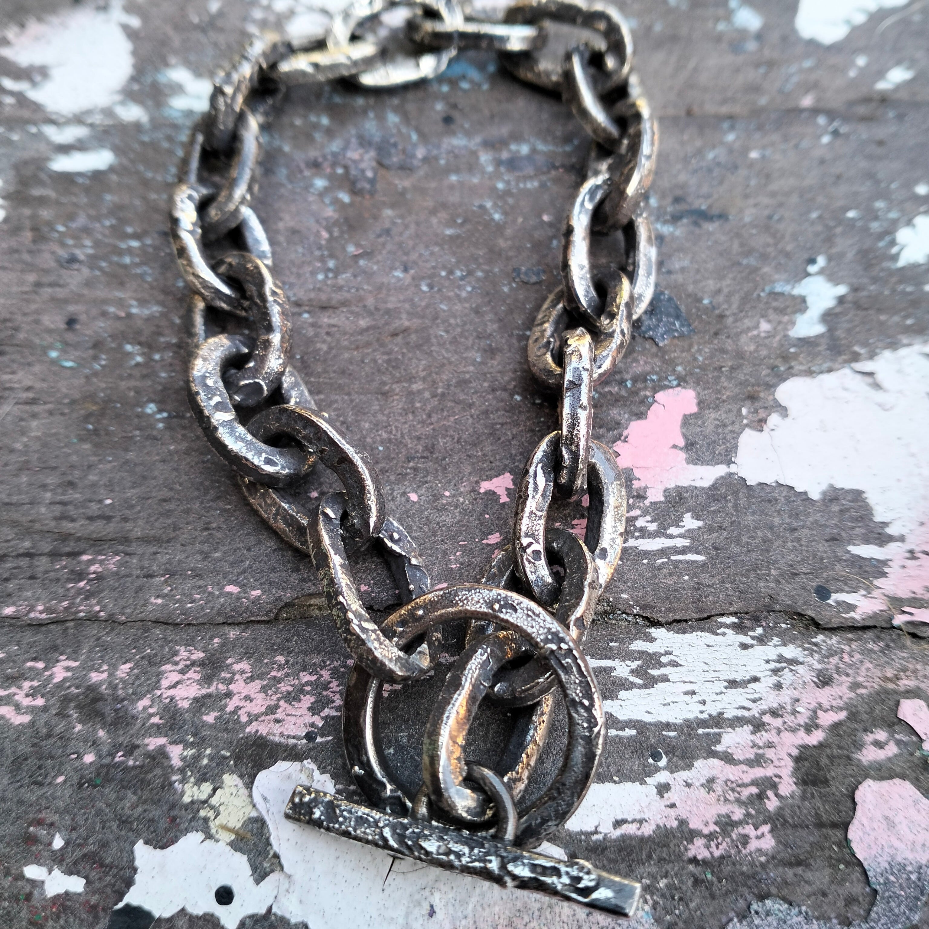 Silver textured and oxidised chain bracelet on a textured surface